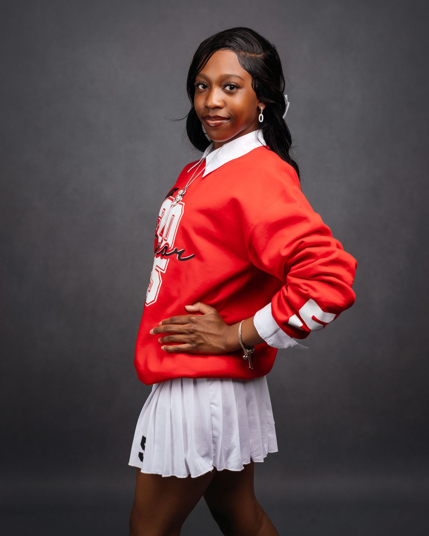 Portrait session in red and white cheerleader uniform against dark background showing dynamic poses.