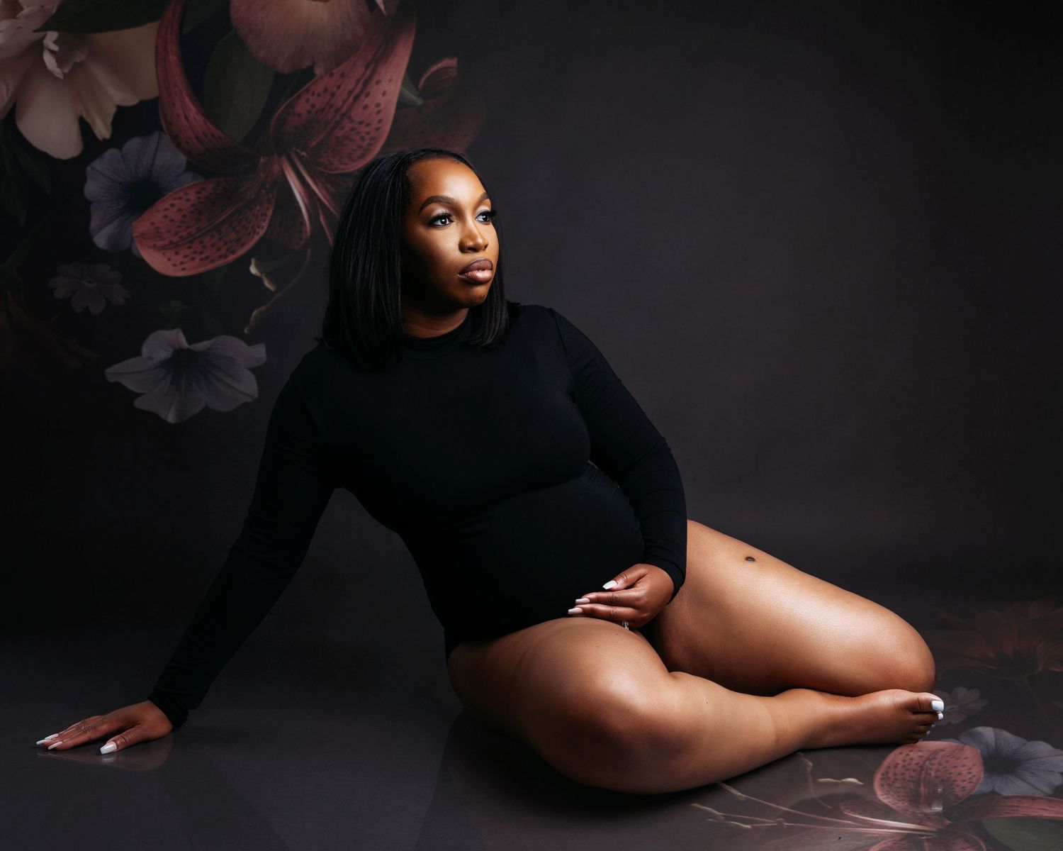 Artistic maternity portrait with moody lighting and black clothing.