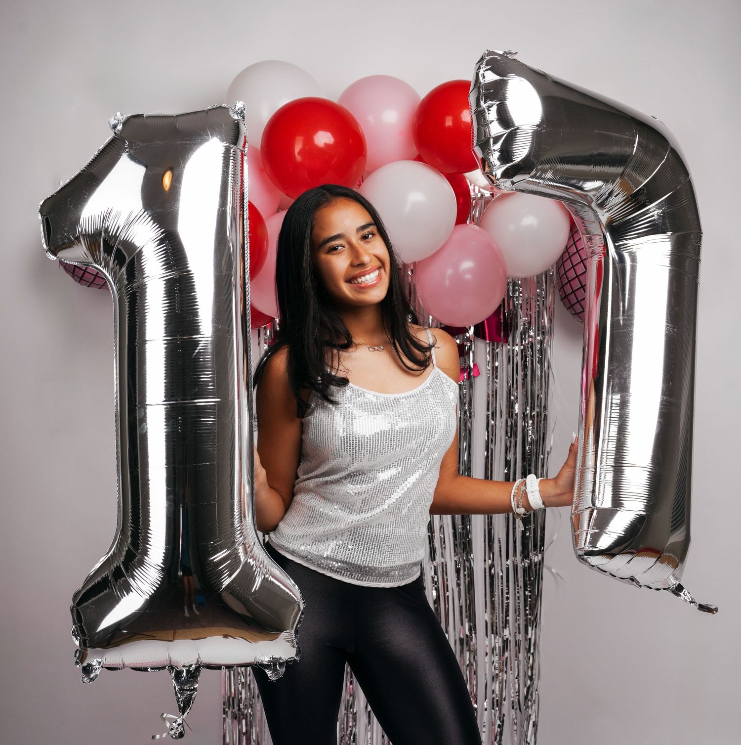 Party scene with silver number balloons and red and white balloon arch decorations.