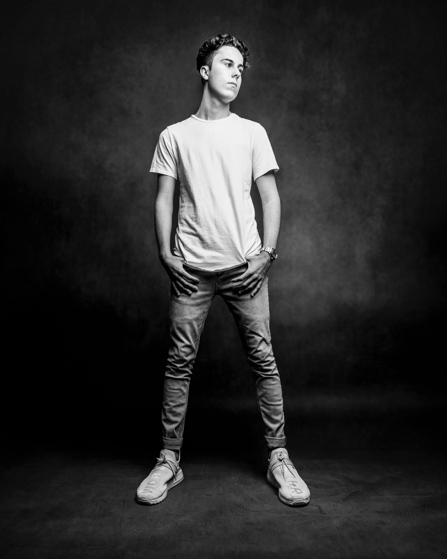 Black and white photo series showing casual poses in white t-shirt and jeans against dark background.