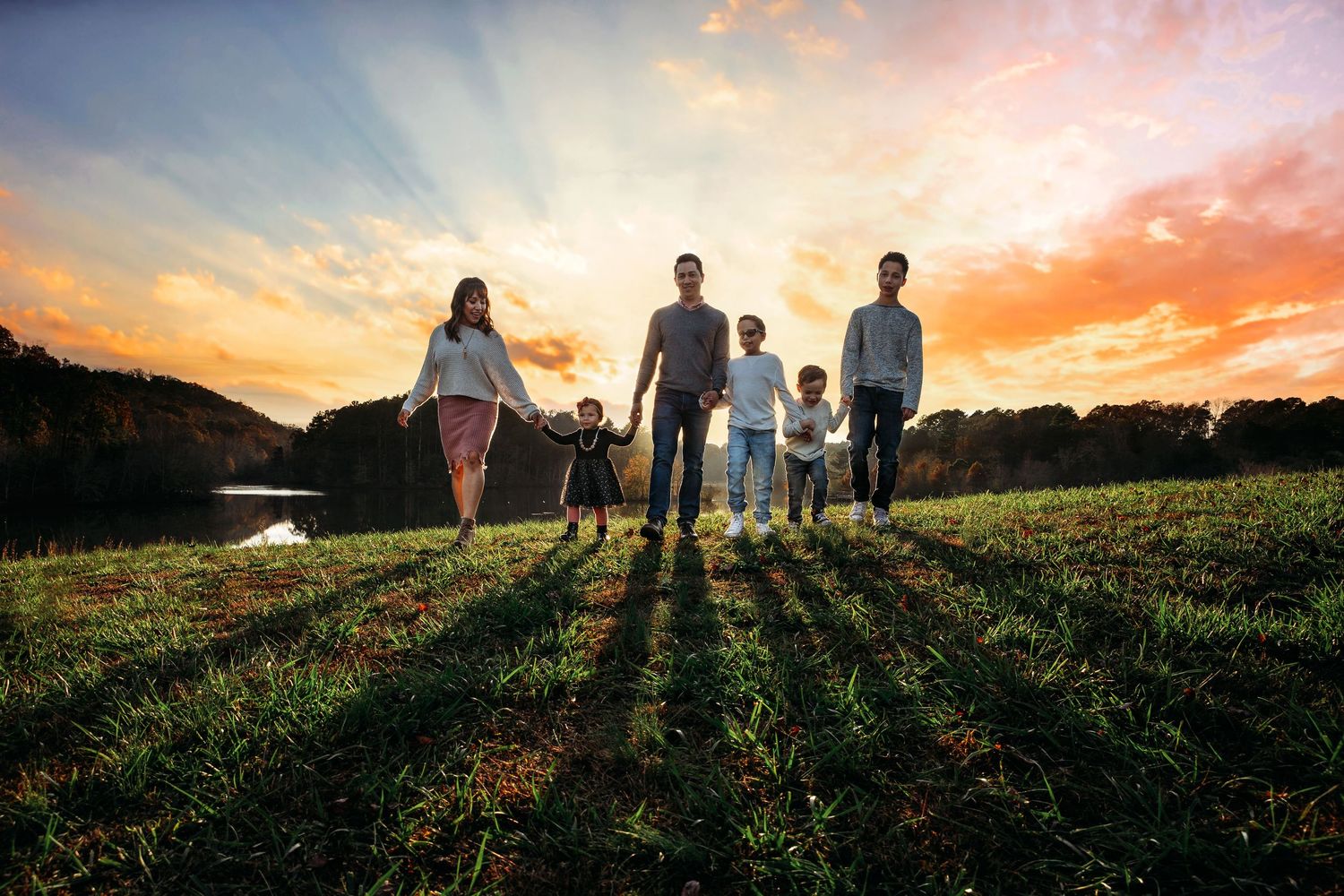 Silhouettes of a family walking together at sunset in a grassy field.