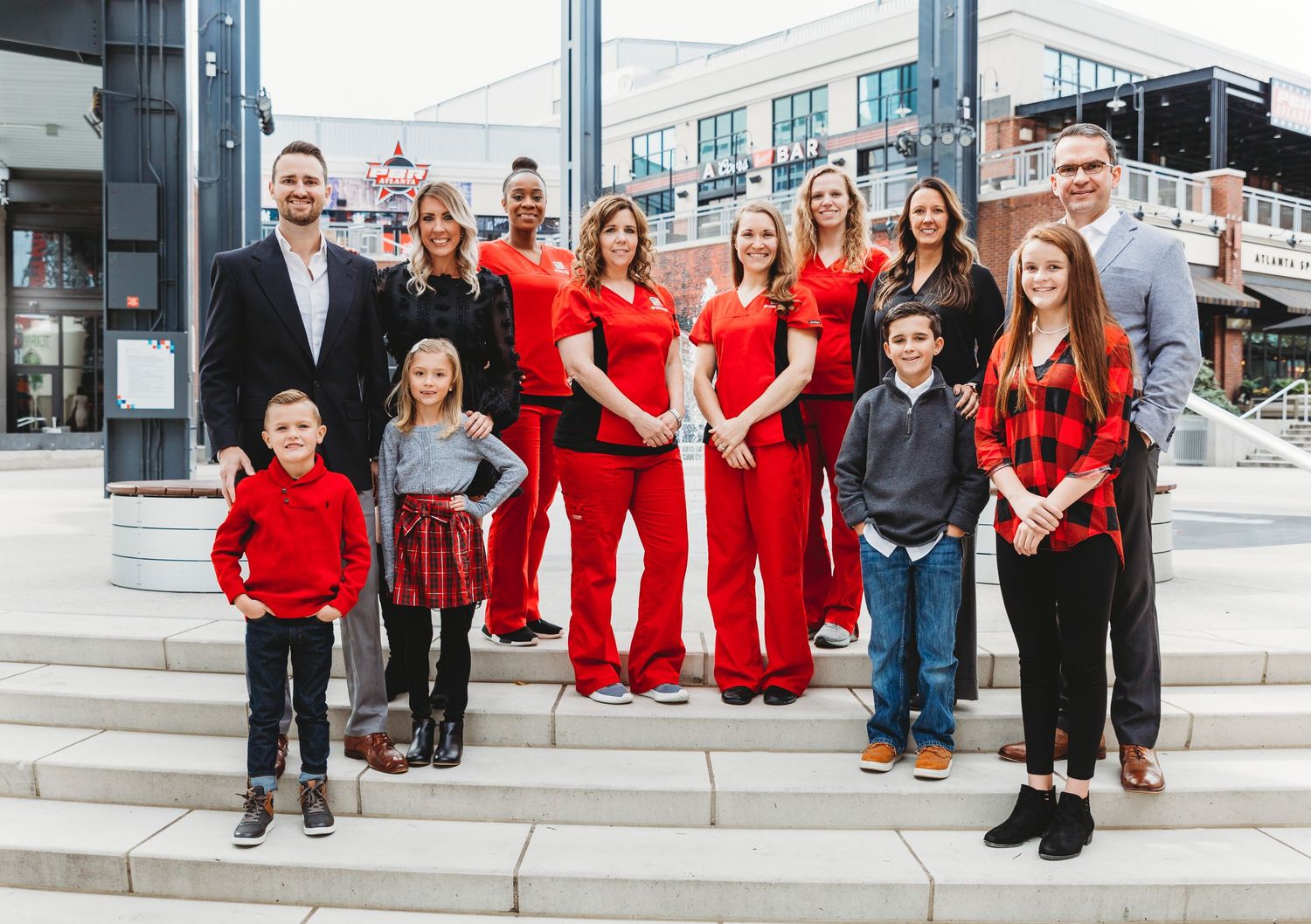 Group photo showing people in coordinated red outfits posing together on outdoor steps.