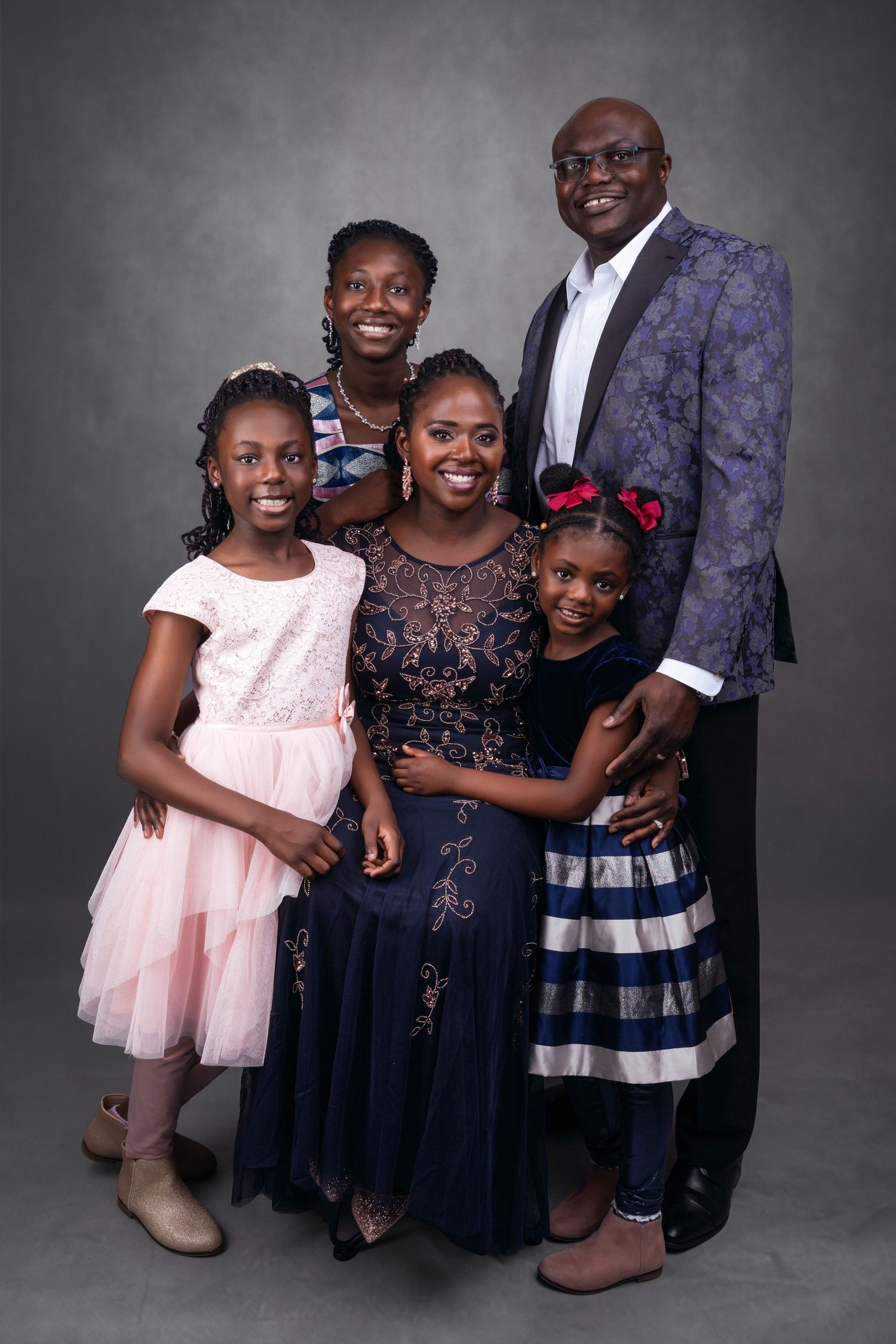 Family portrait featuring coordinated formal wear in studio setting.