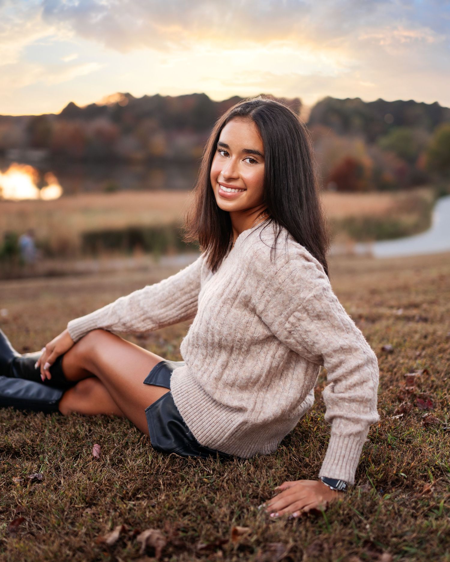 Casual outdoor portrait session in cream sweater on autumn grass at sunset.