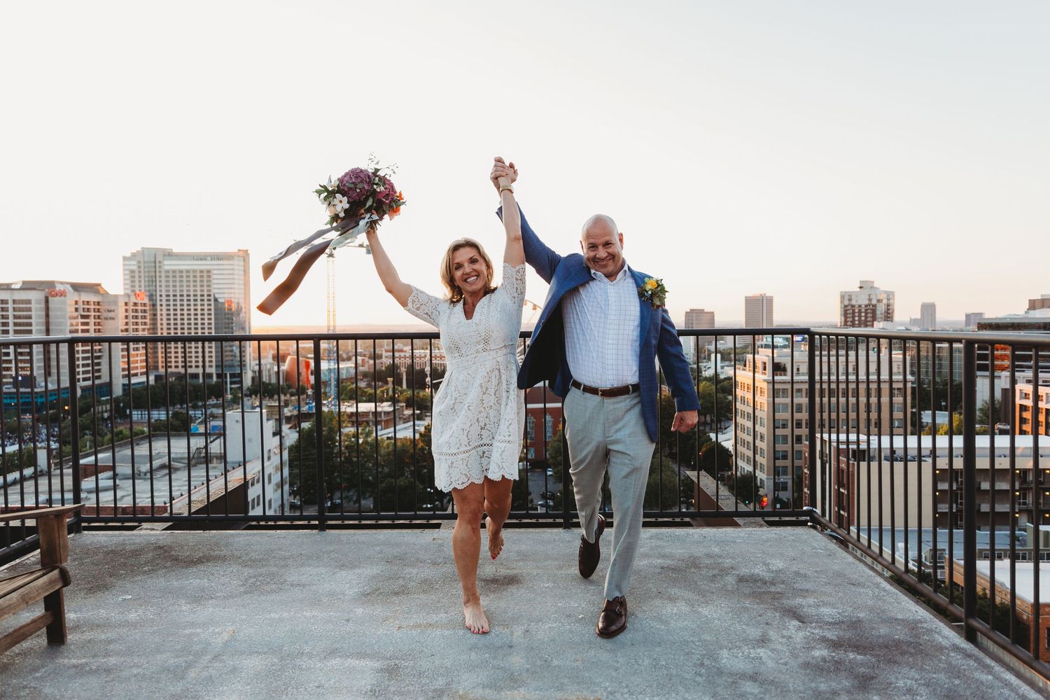 Wedding party members walking and posing on rooftop venue with city views.