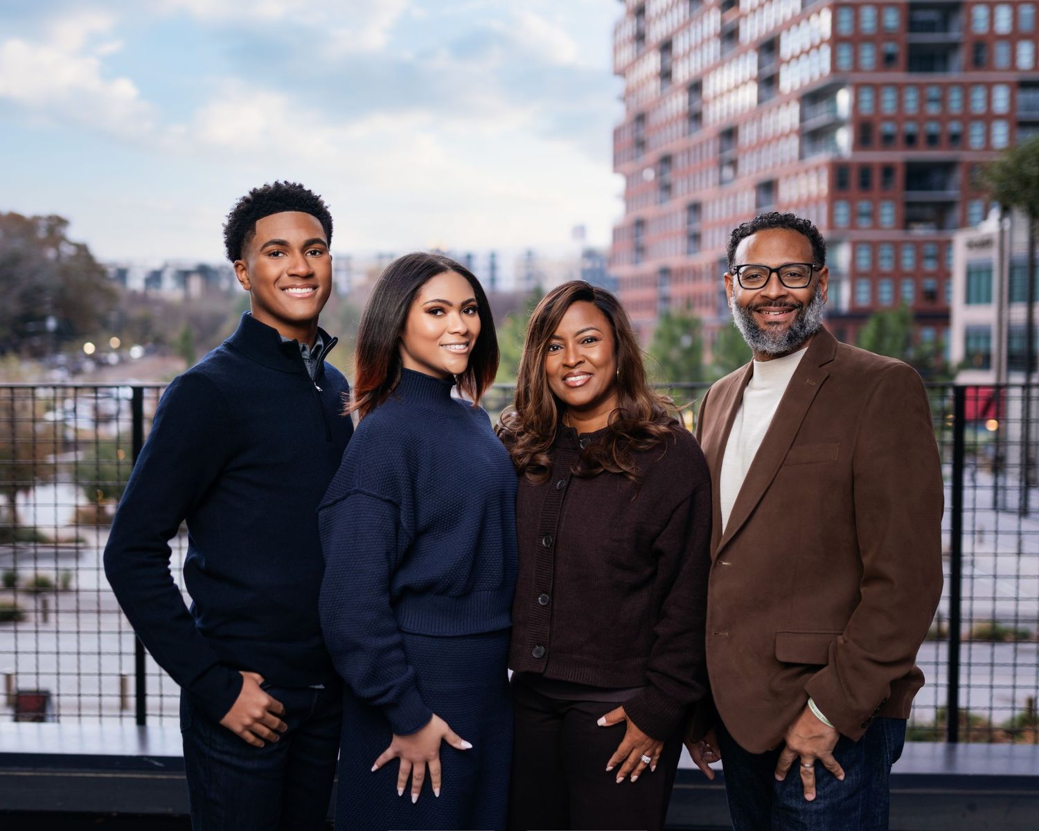 Group portrait of four people in winter coats against urban backdrop.