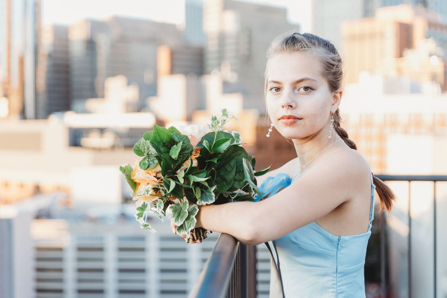 Wedding party members in blue and white attire posing on an urban rooftop.