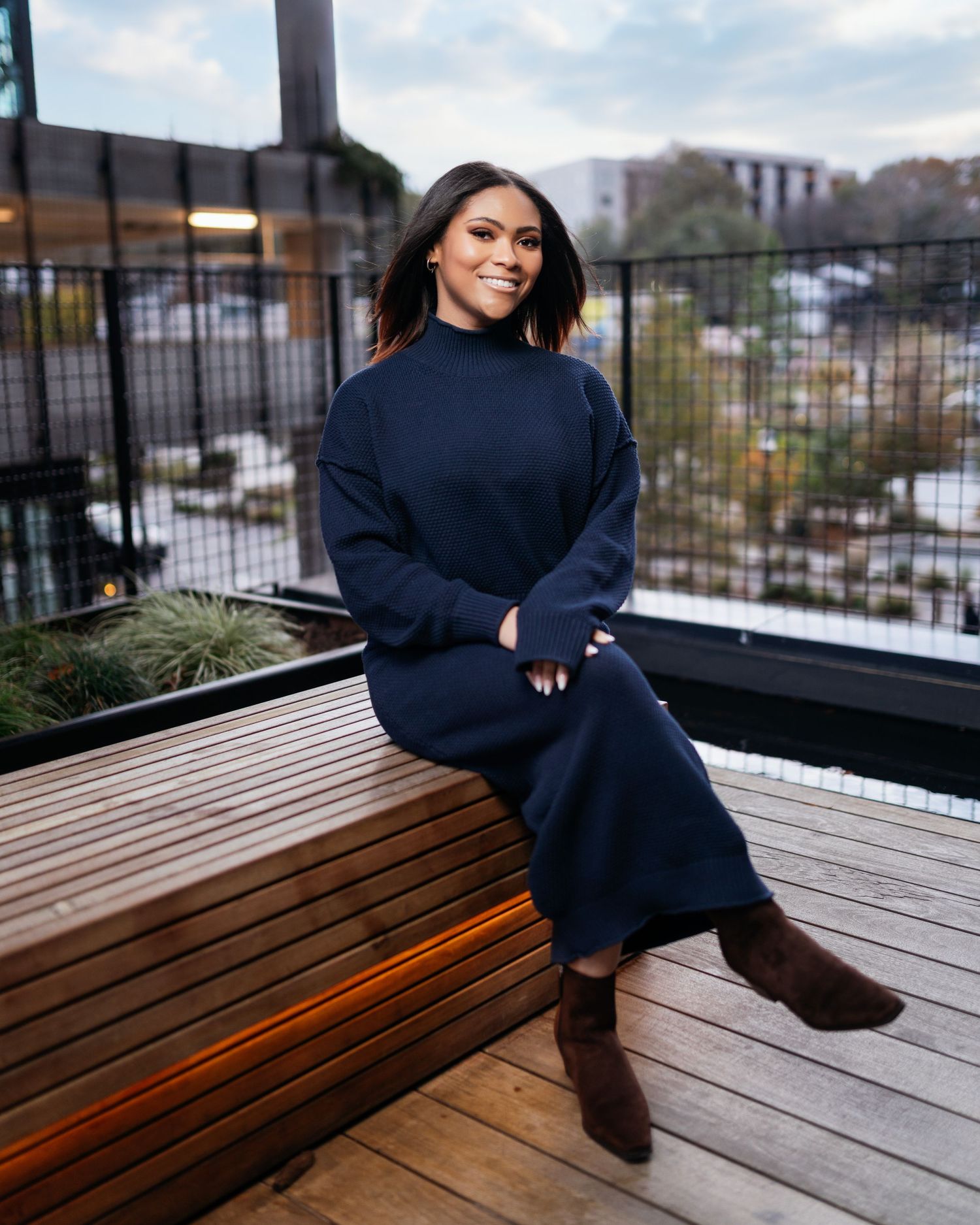 Person in navy sweater relaxes on wooden deck during outdoor photoshoot.