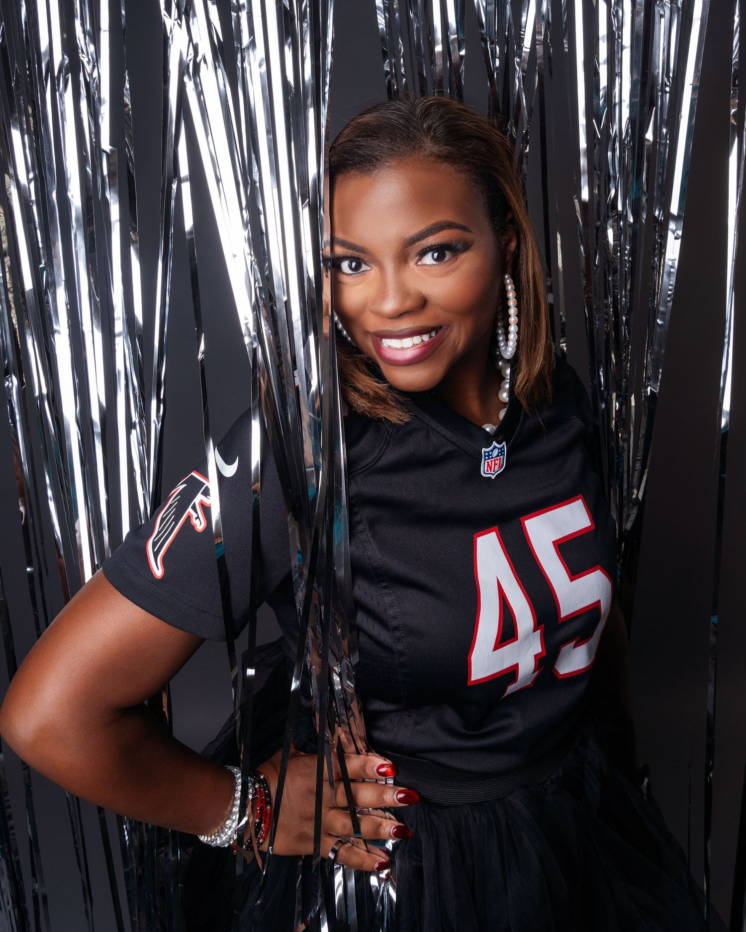 Energetic poses in black NFL jersey number 45 against silver streamer background.