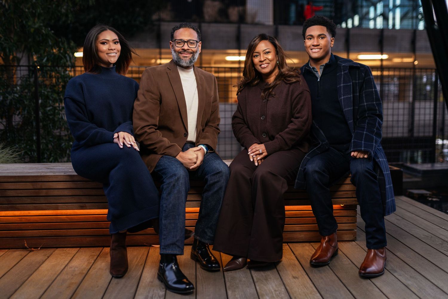 Group sitting together on outdoor wooden bench during evening photoshoot.