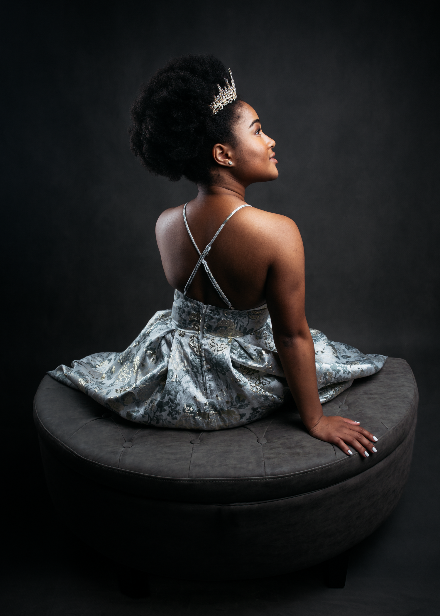 Artistic fashion poses showcase a shimmering silver evening gown on dark backdrop.