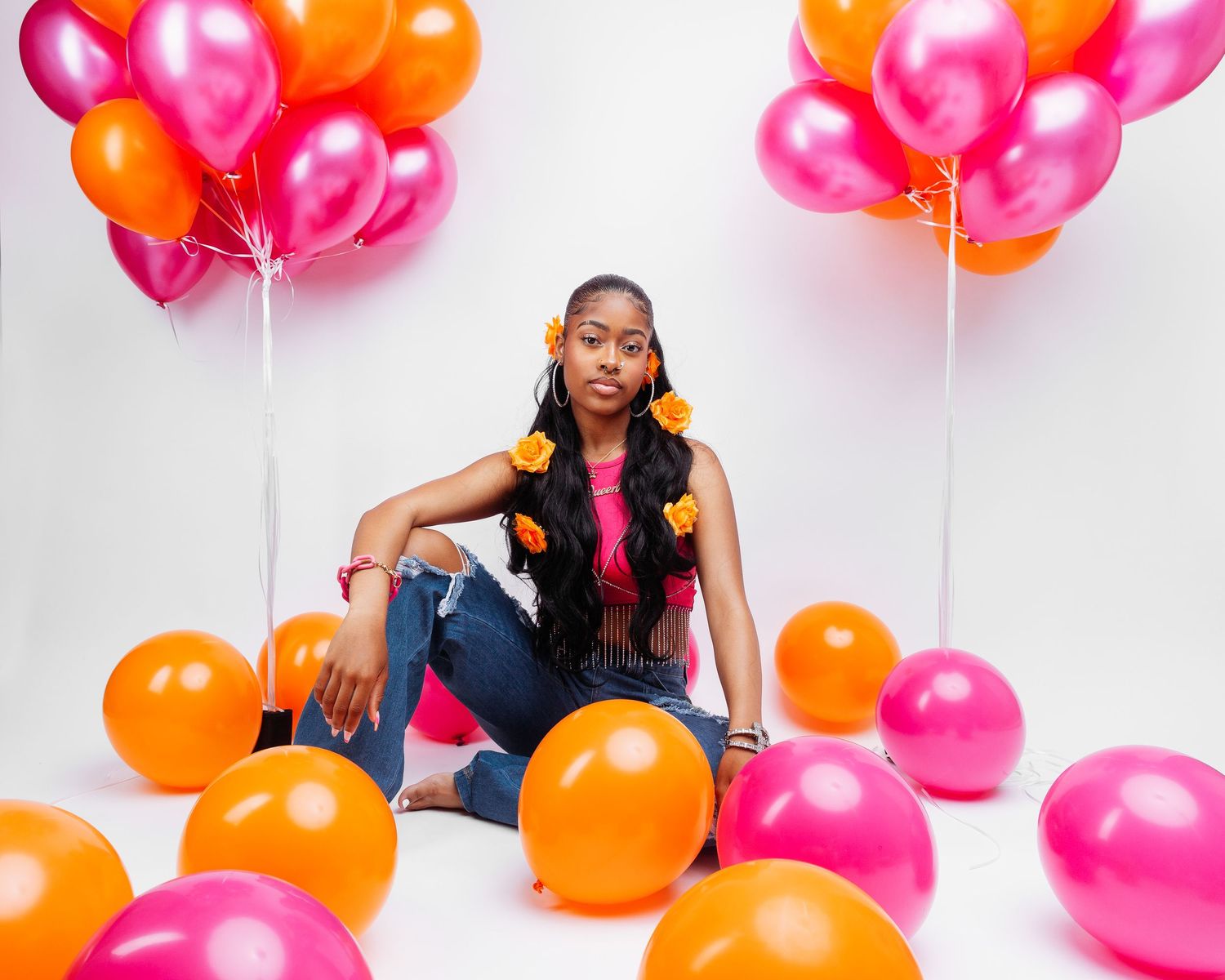 Vibrant pink and orange balloons create a festive backdrop for a glamorous photo session.