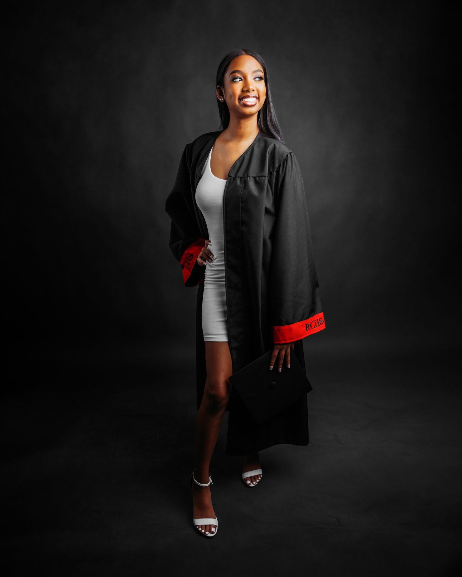 Full length graduation photos in black cap and gown against dark backdrop.