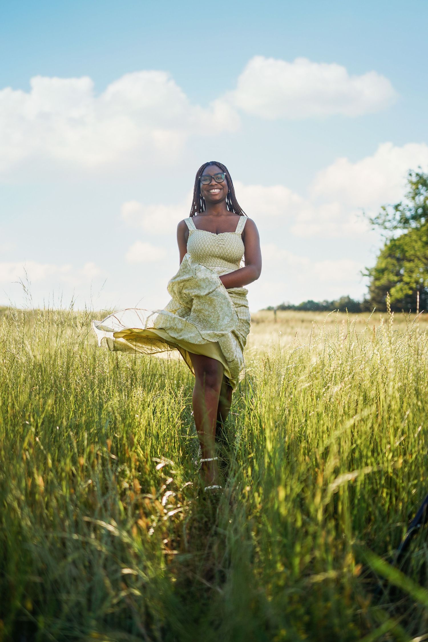 Person in yellow dress running through tall wheat field under bright blue summer sky.