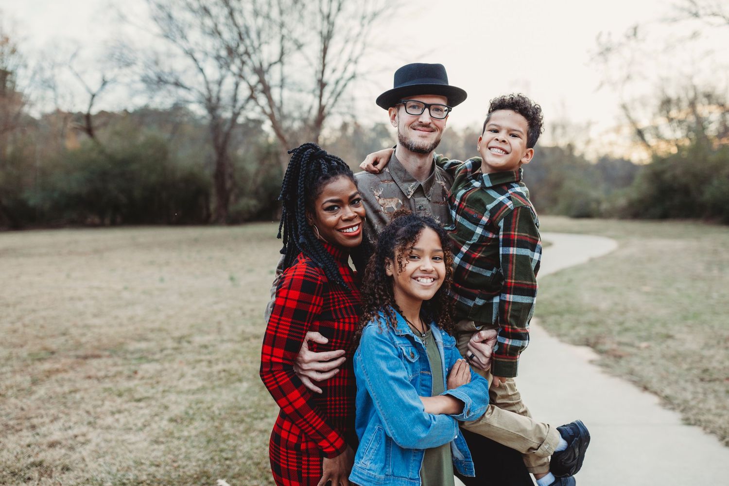 A joyful group hug captured outdoors on a path surrounded by autumn trees.