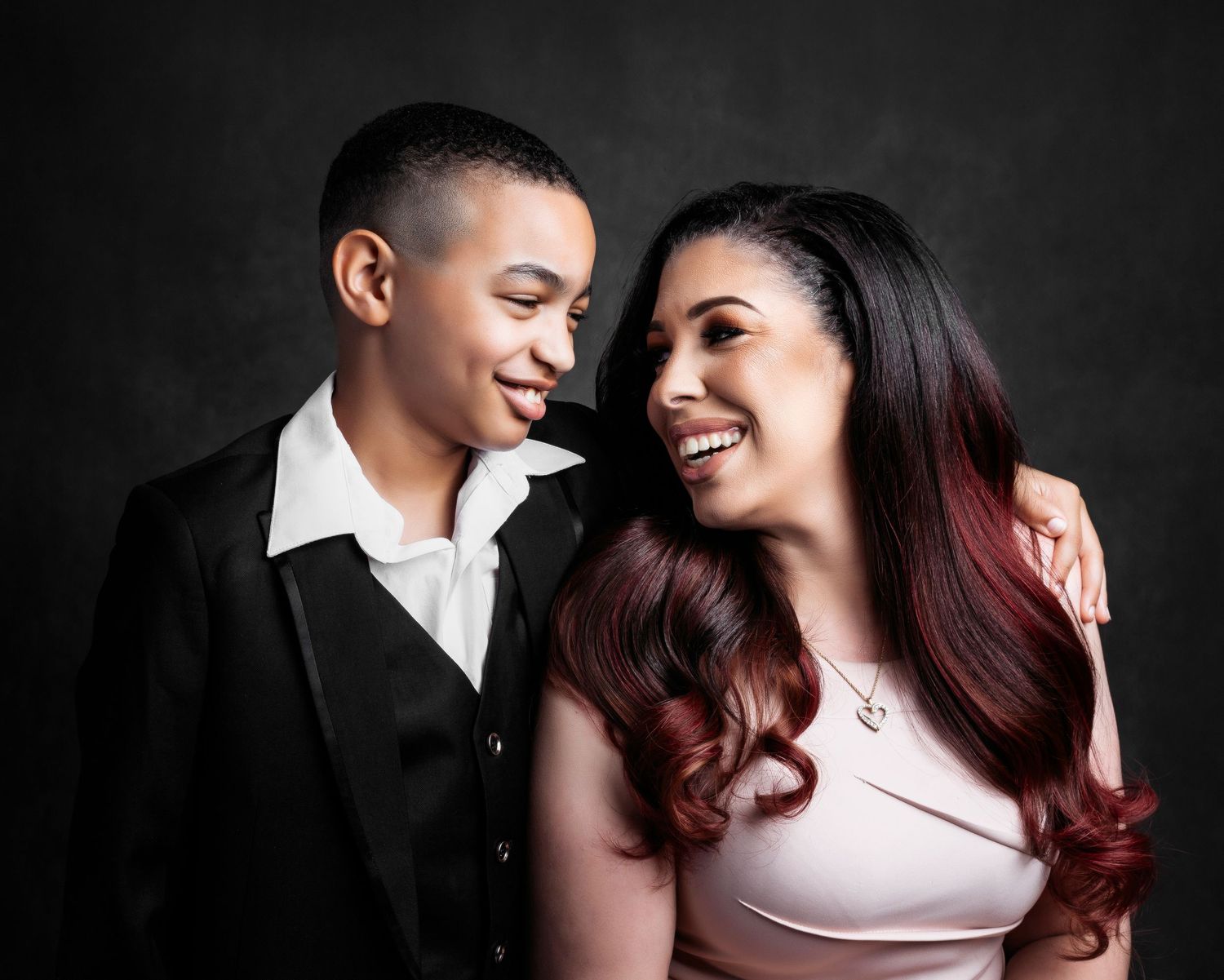 Intimate portrait of a couple sharing a joyful moment against dark background.