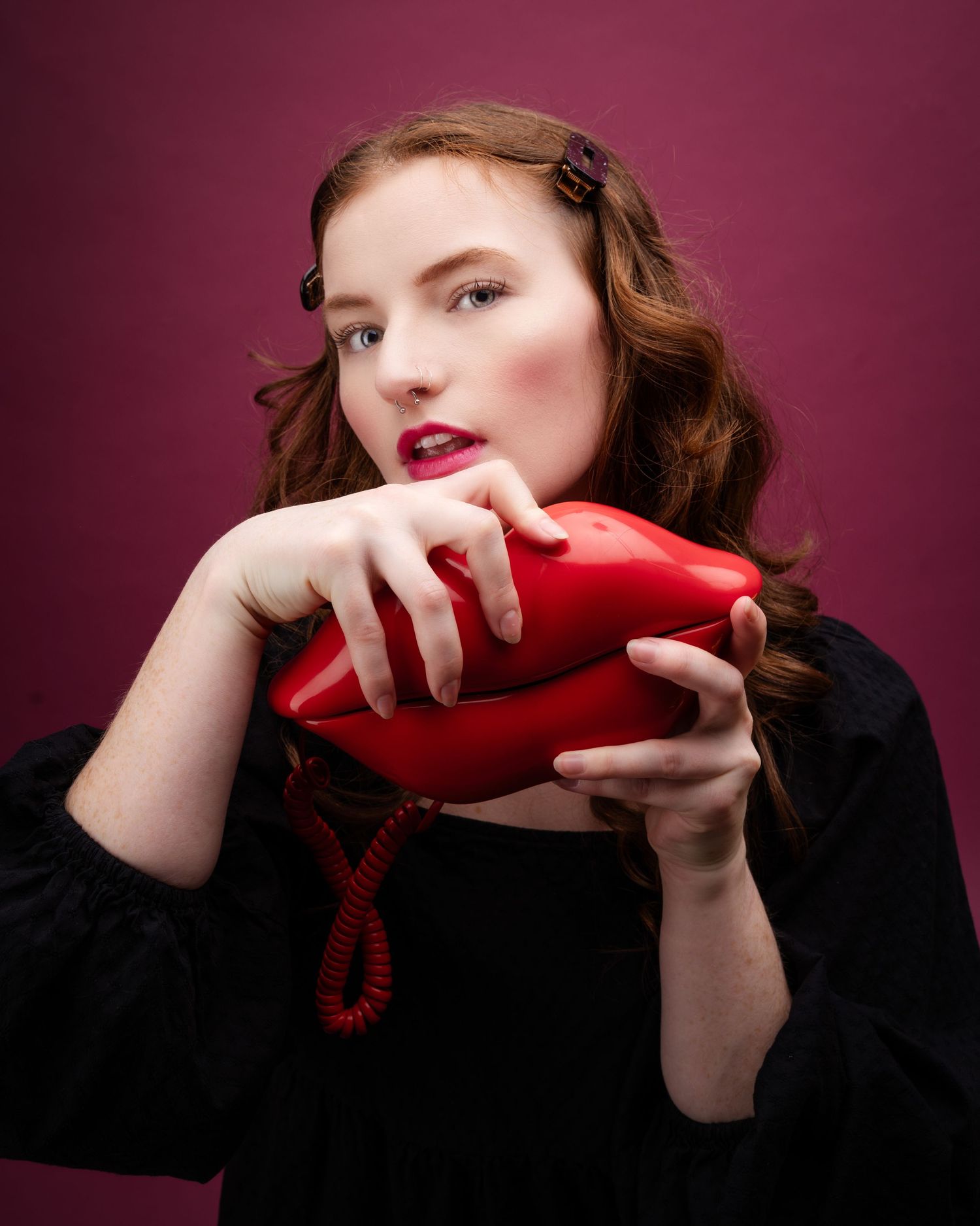 Creative portrait series with a red vintage telephone against a burgundy background.