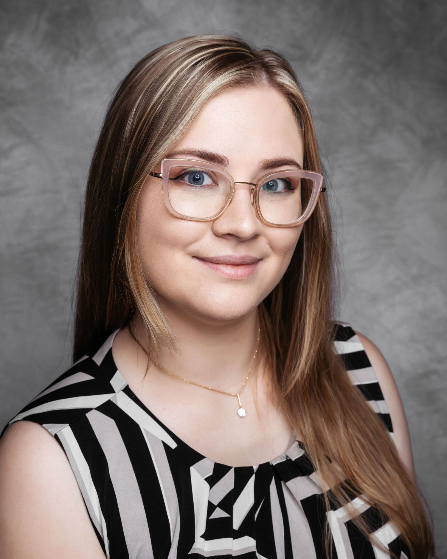 Professional portraits of person wearing black and white striped top and glasses.