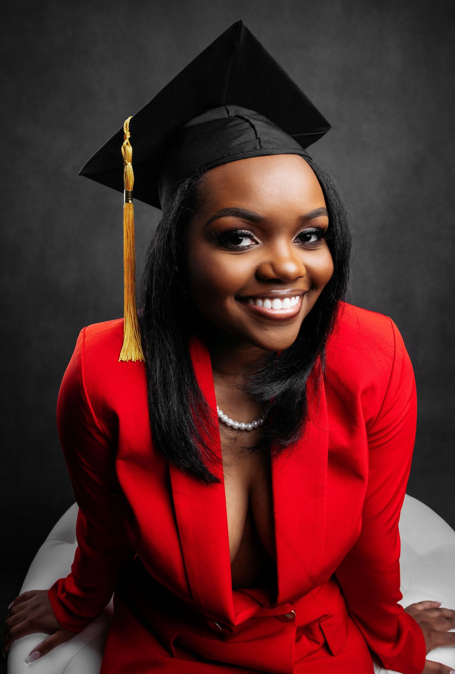 Professional graduation portraits in red blazer and black cap with gold tassel.