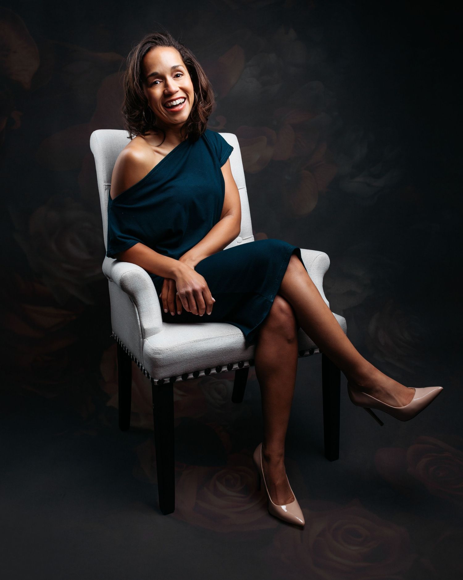 Elegant portrait session on white chair against dark background.