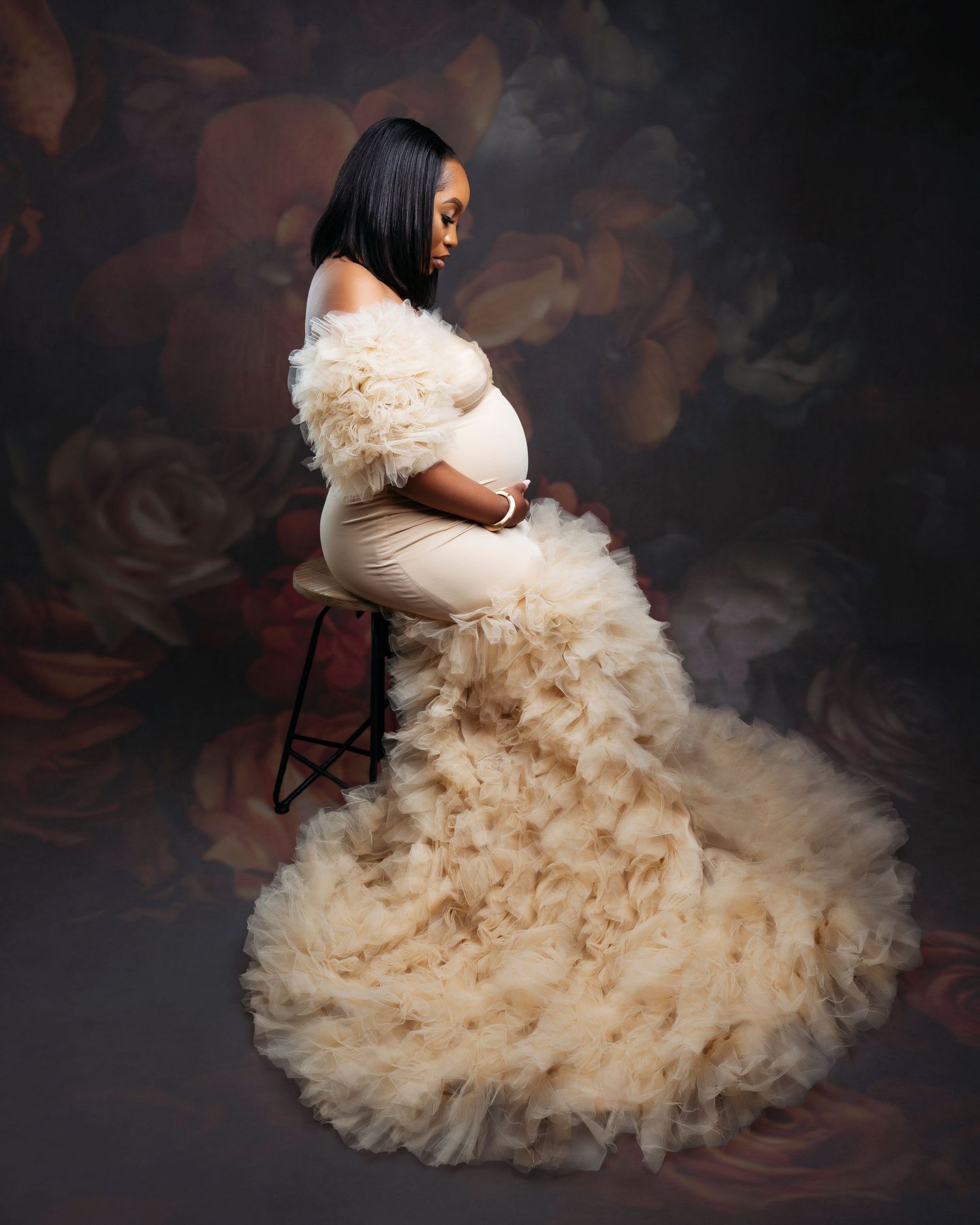 Elegant portrait session featuring flowing cream-colored tulle gown against dark background.