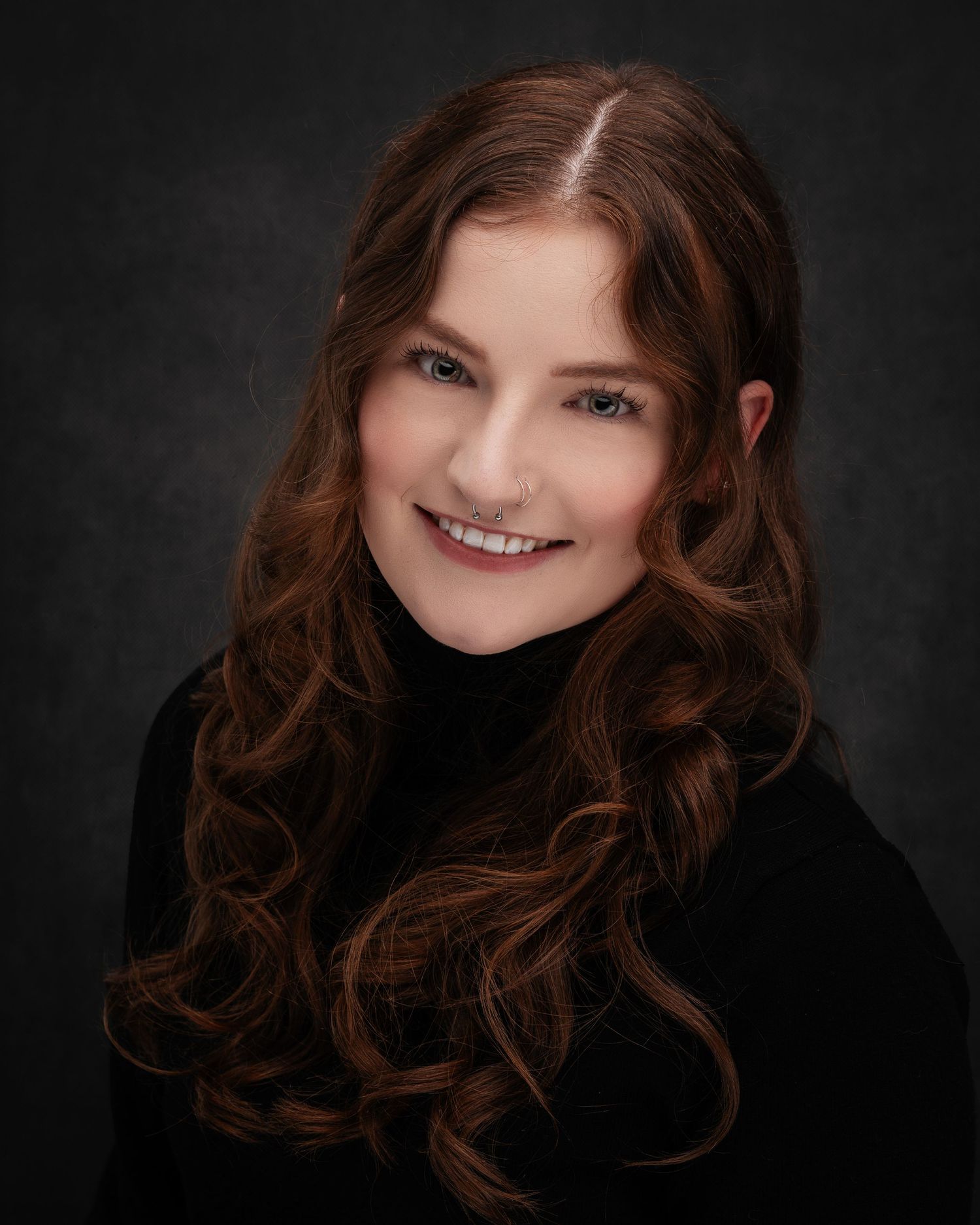 Studio portrait with dark background showing curled hair and black clothing.
