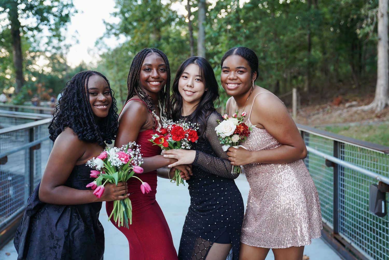 Group photo of bridesmaids holding bouquets at outdoor wedding celebration.