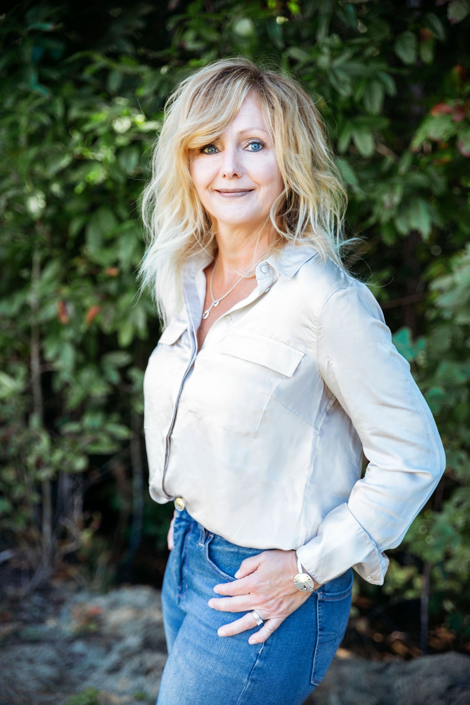 Casual outdoor photos of person in white shirt and jeans posing near greenery.