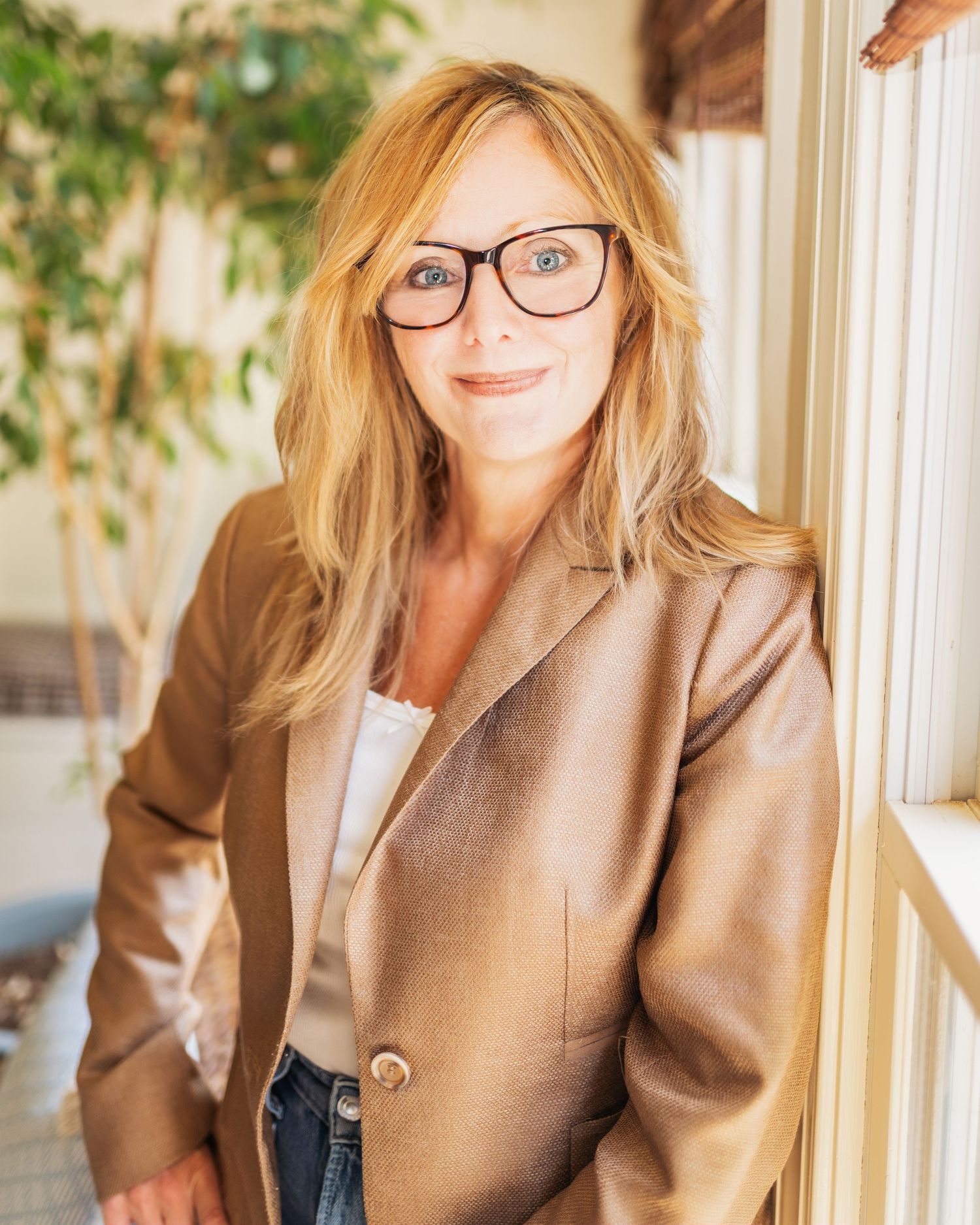 Professional headshots of a person in a brown blazer and glasses against a light background.