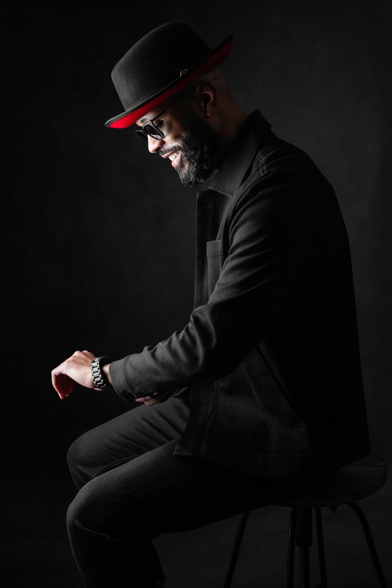 Silhouette portrait series of person in dark clothing and red cap against black background.