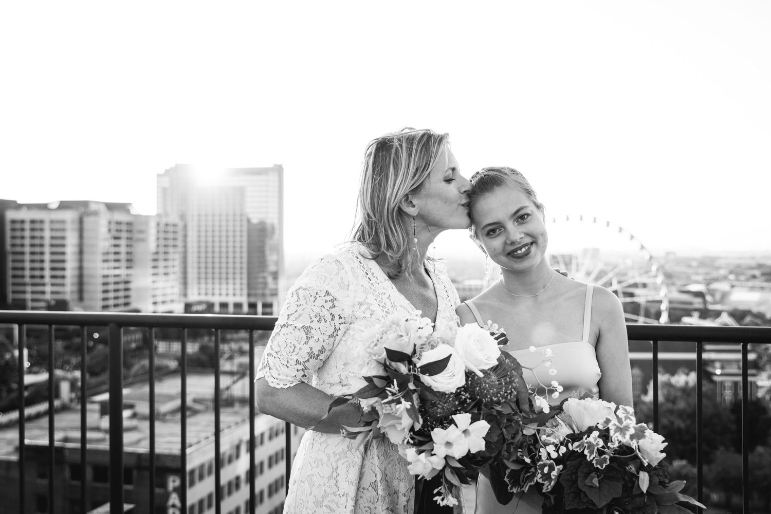 Wedding party posing together on a rooftop with white floral bouquets.