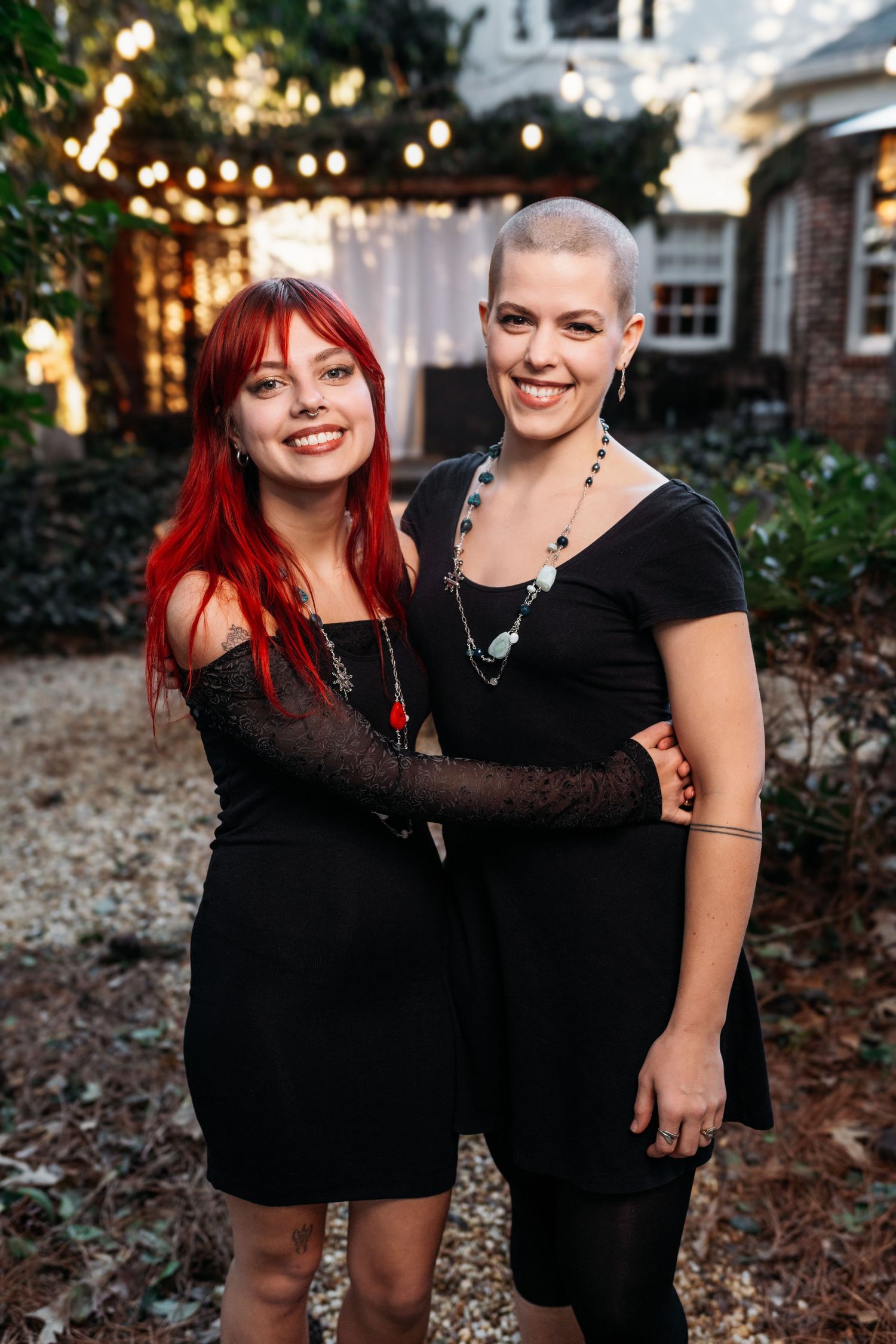 Two people in black outfits share a joyful moment during outdoor photo session.