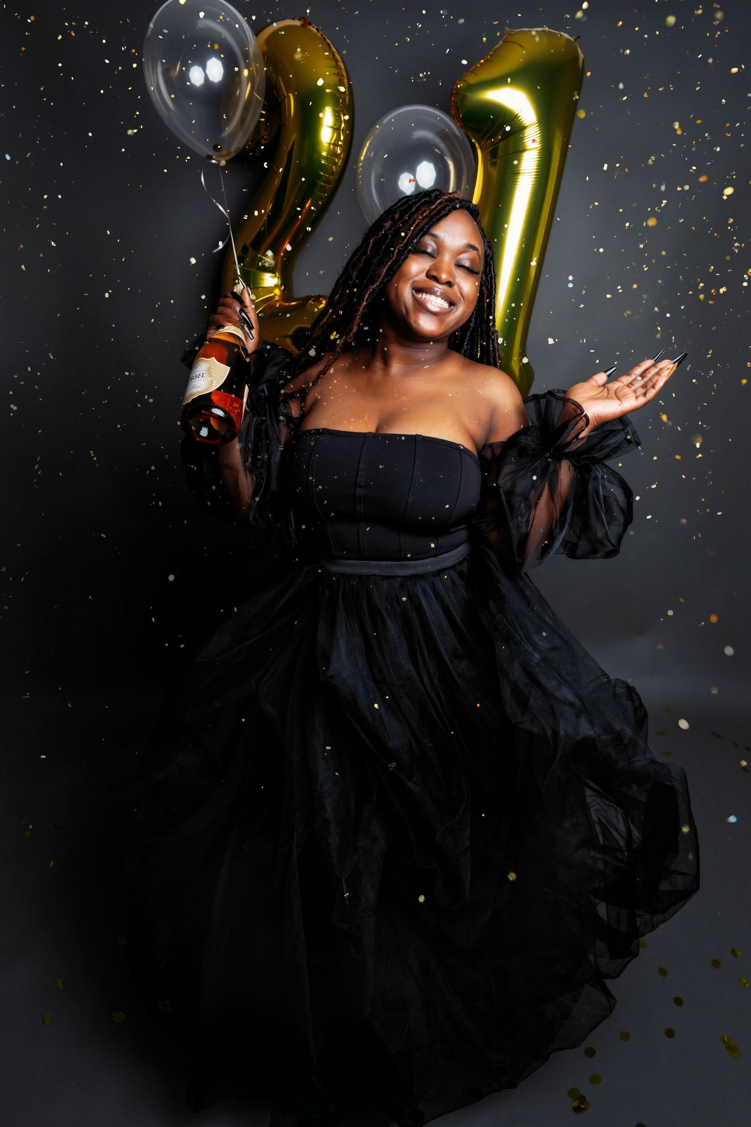 Celebratory portrait session with gold balloons and confetti against a dark background.