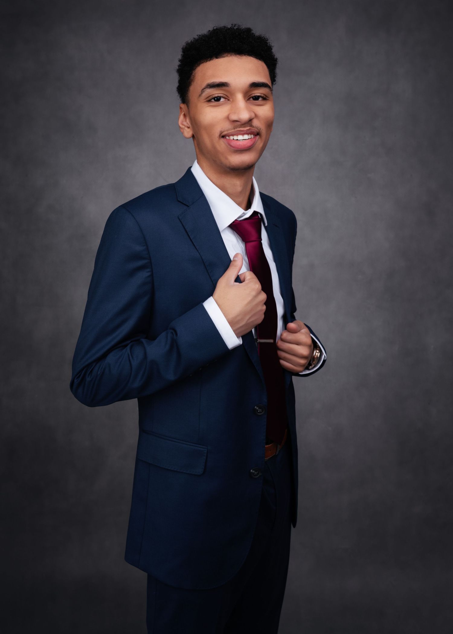 Professional headshot series featuring navy suit and tie against grey studio background.