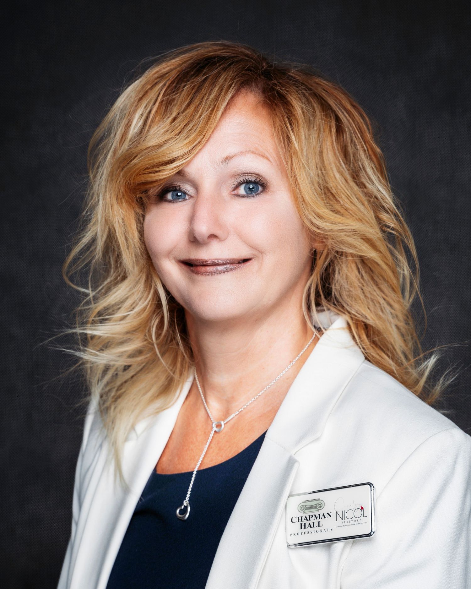 Professional portraits of person in white blazer against dark background.