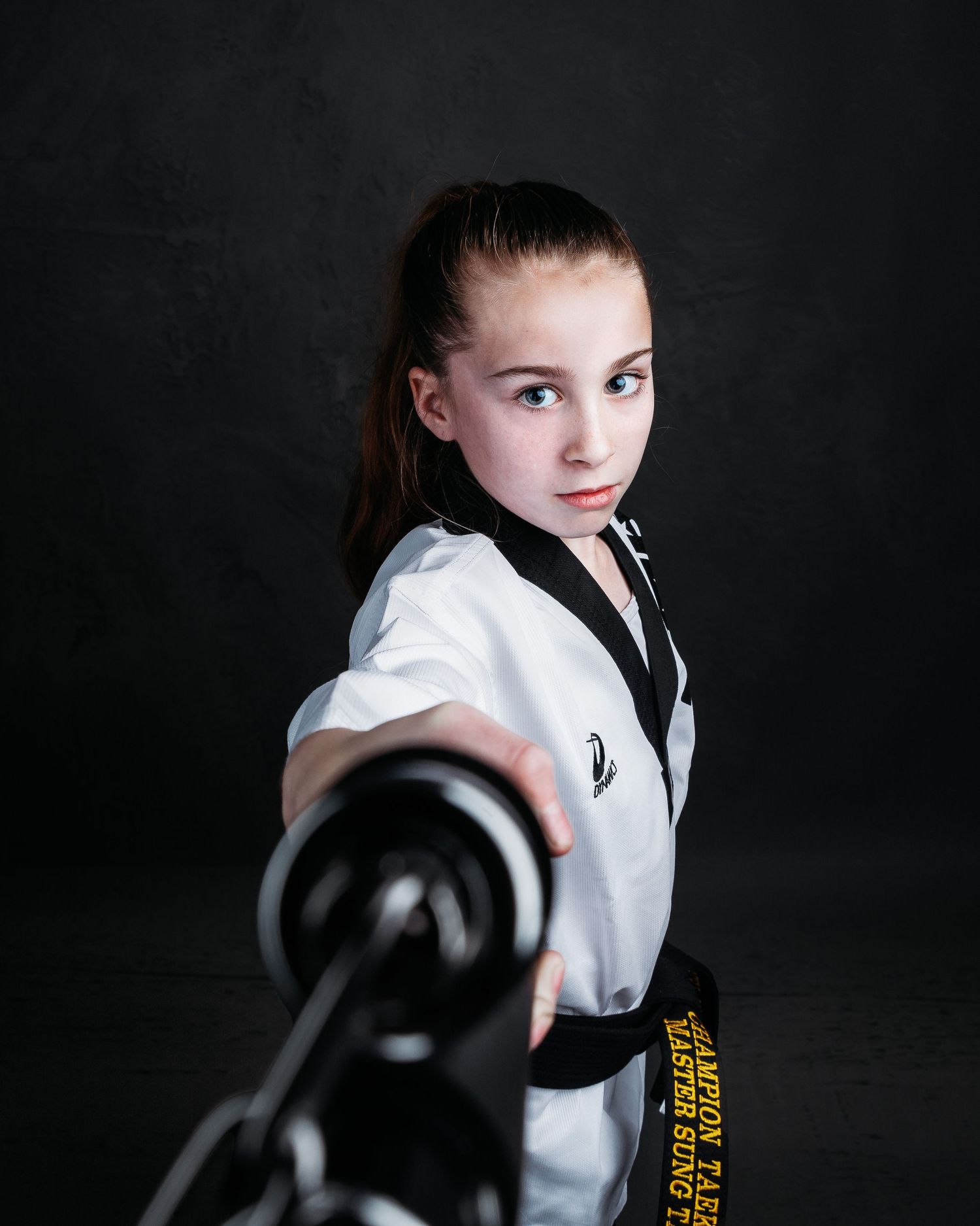 Martial arts student in white uniform practicing kicks against dark background.