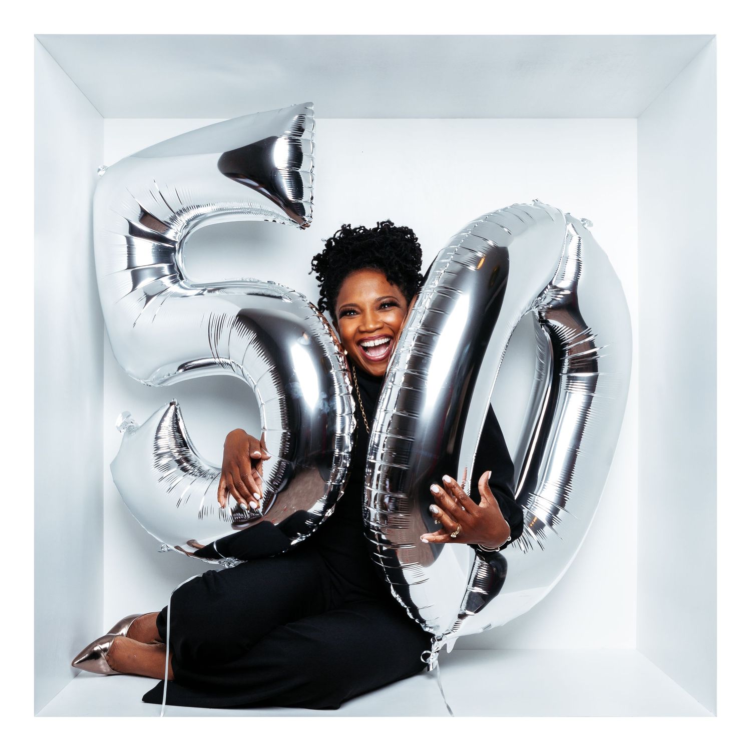Playful studio portraits with silver balloon letters and celebratory poses in white room.