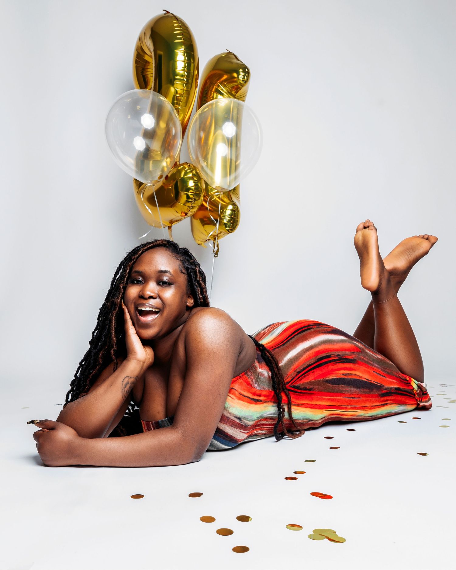 A festive photo shoot with gold number balloons and rose petals against a white backdrop.