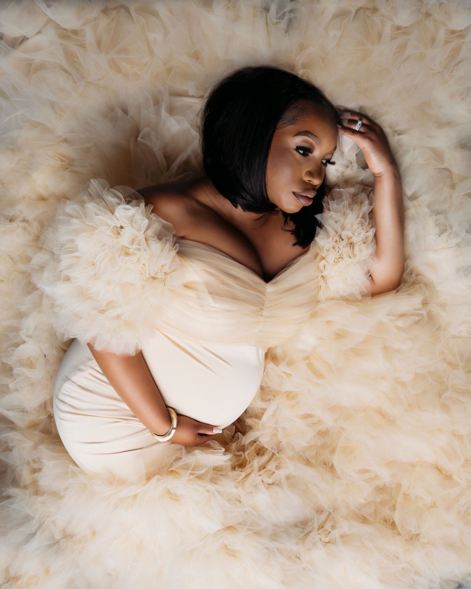 Dreamy bridal portrait series with subject lying in cream-colored tulle fabric.