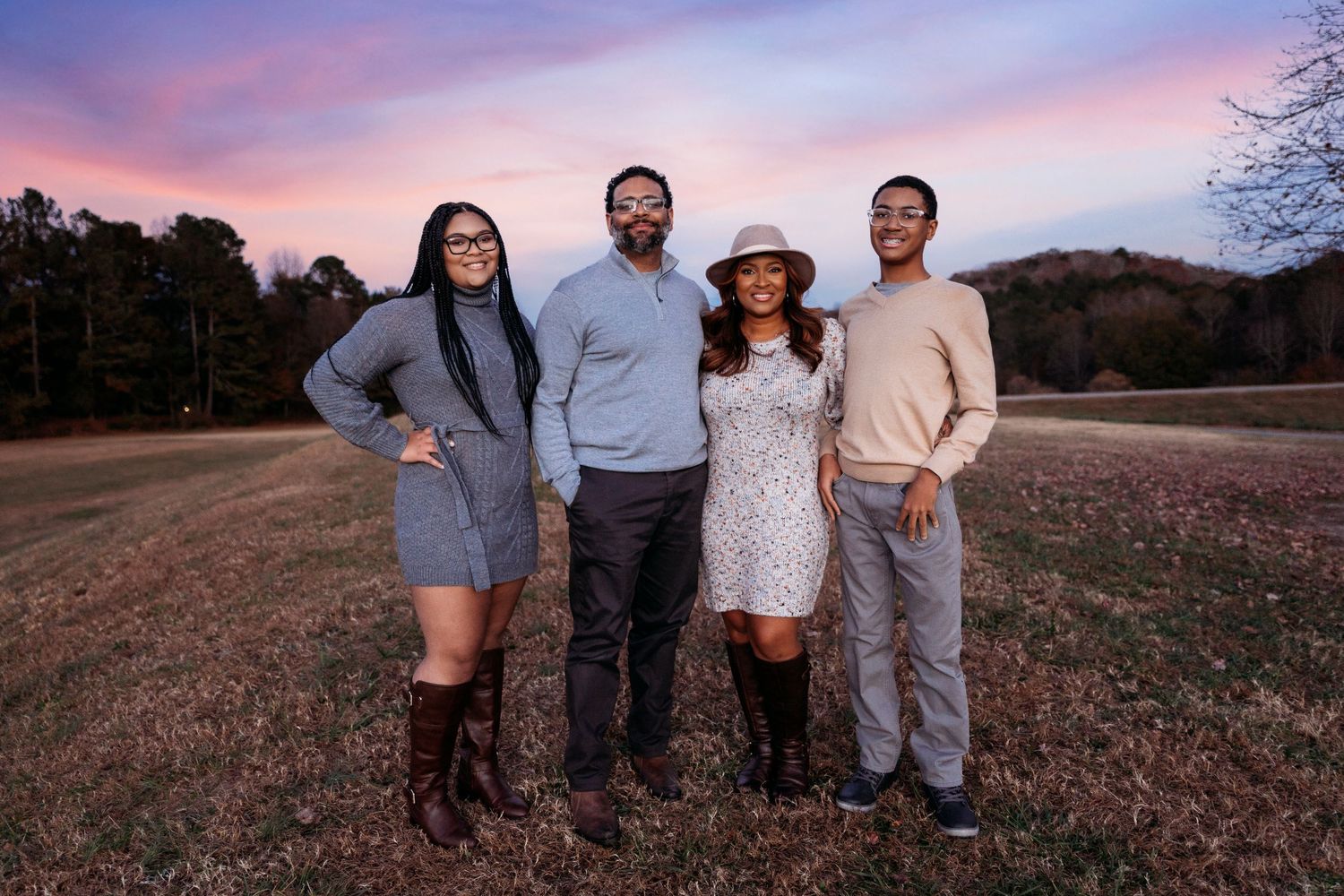 Group photo session at sunset with people wearing coordinated casual outfits in a field.