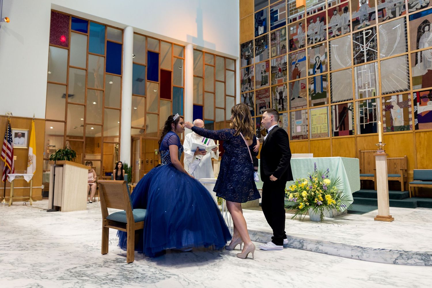 Church interior with wooden pews and photo-covered walls during wedding ceremony.