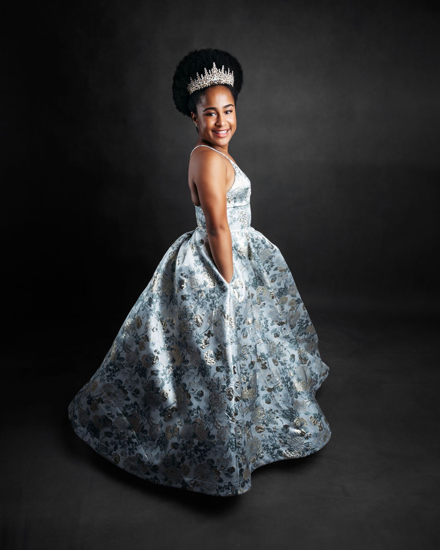 Elegant silver ball gown sparkles in dramatic poses against dark background.