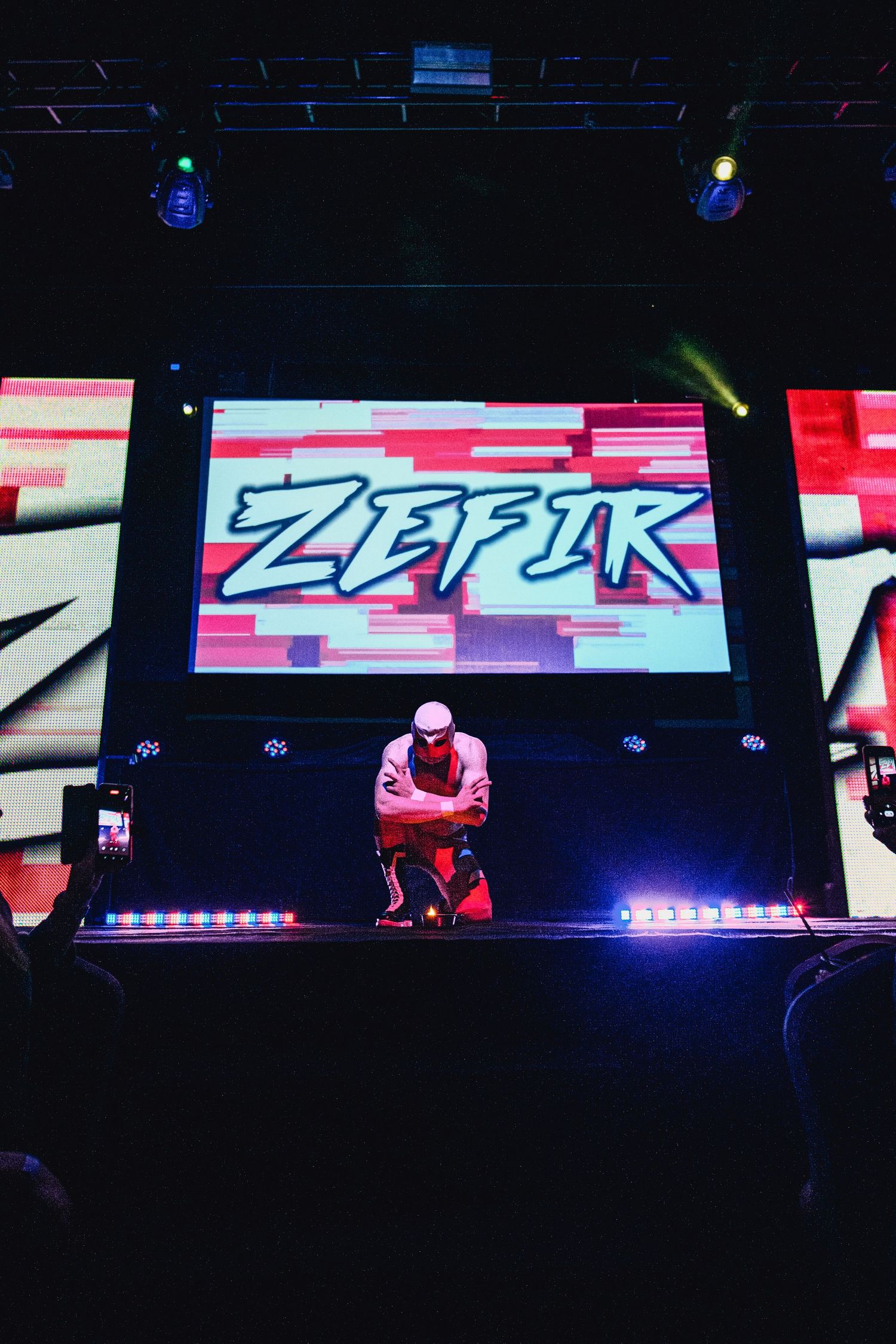 Dark arena with illuminated display screens showing 'ZEPIK' text and red lighting effects.