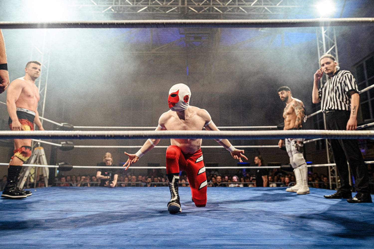 Wrestling match action sequence showing competitors grappling in a blue-lit arena.