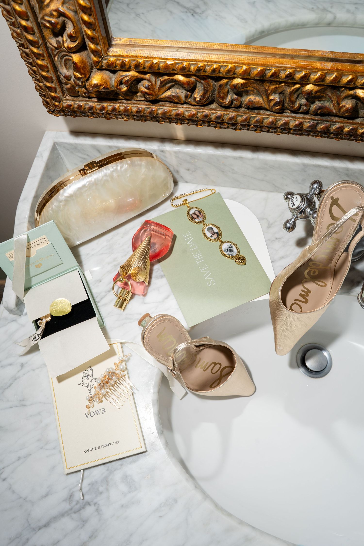 Elegant bridal flat lay on marble sink with Sam Edelman heels, pearl clutch, perfume, and vow booklets.