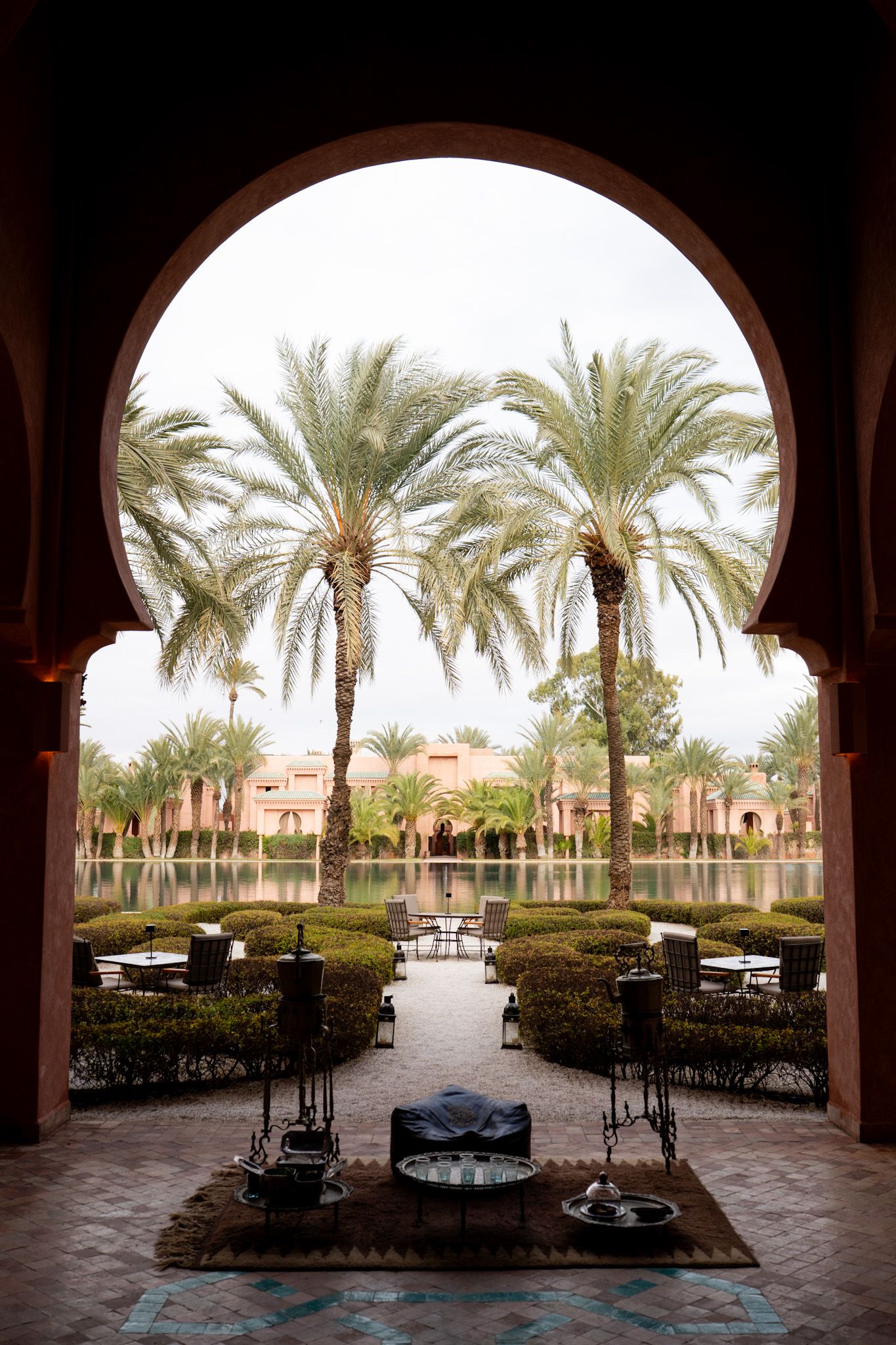 Arched courtyard view of palm trees and landscaping at a Mediterranean-style resort with outdoor seating areas.