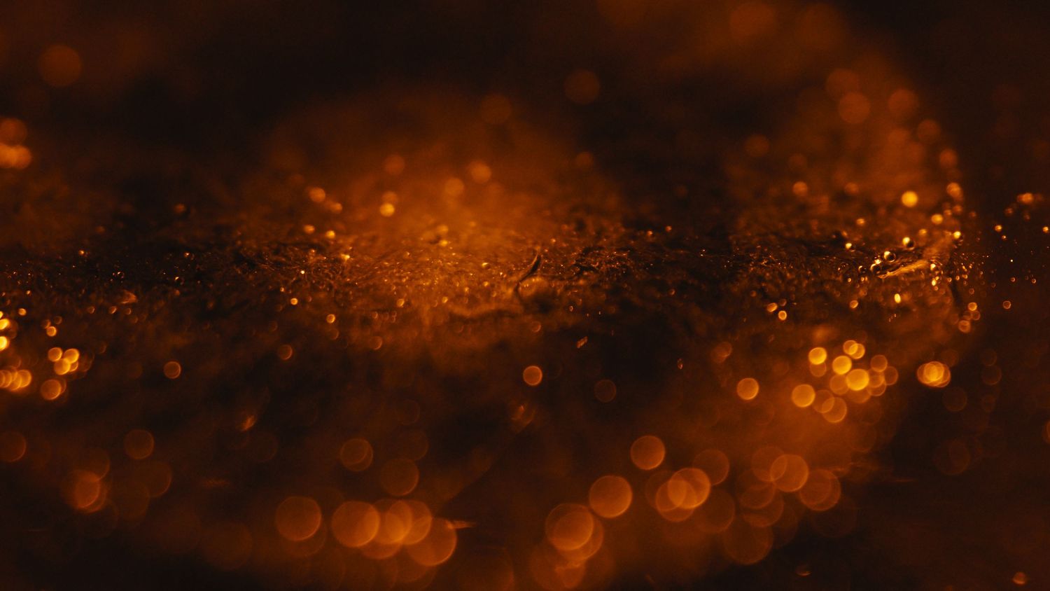 Orange and golden bokeh lights create a dreamy abstract background pattern with glowing circular shapes.