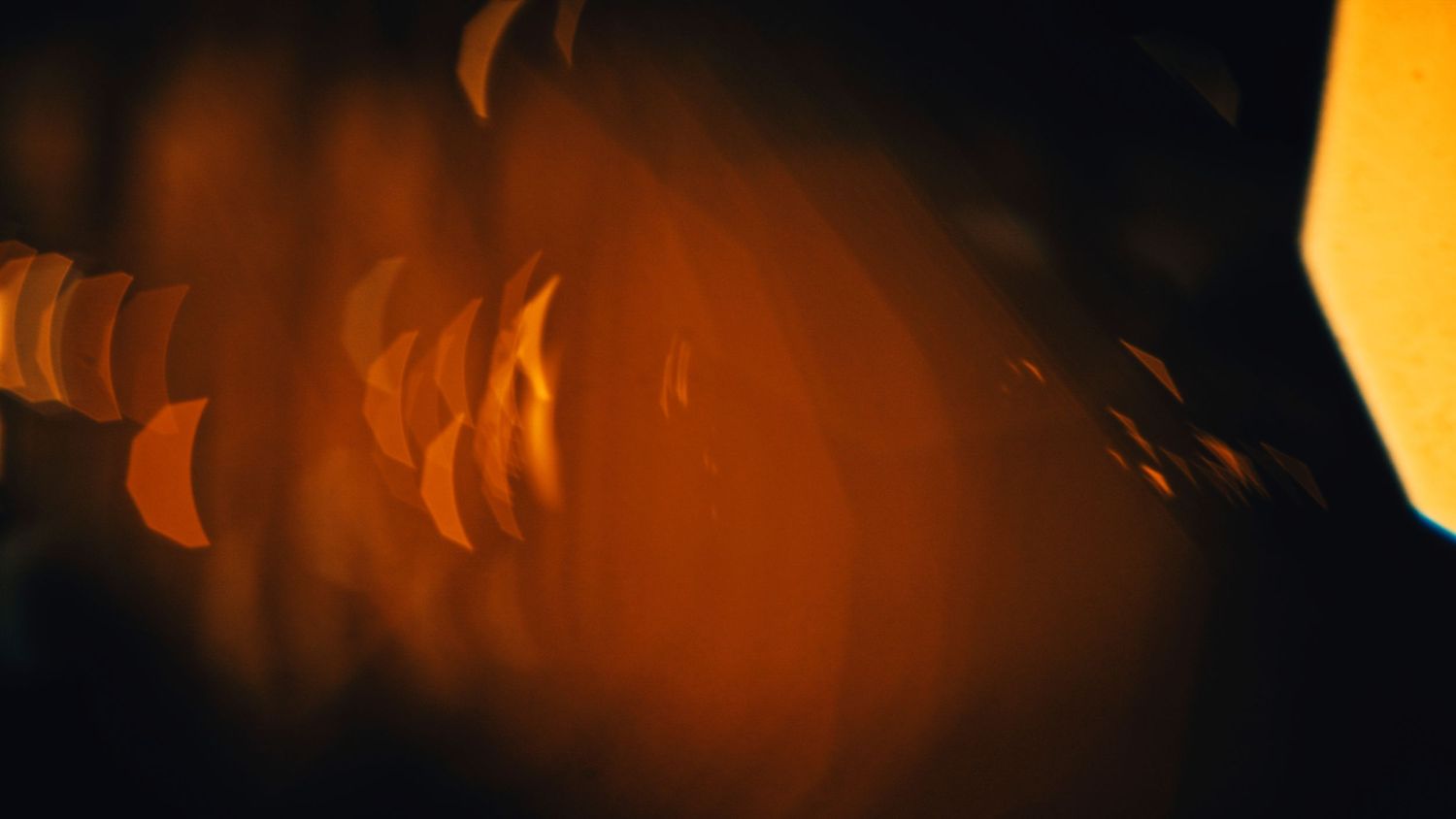An orange smokey wave pattern flows across a dark background creating an ethereal glowing effect.