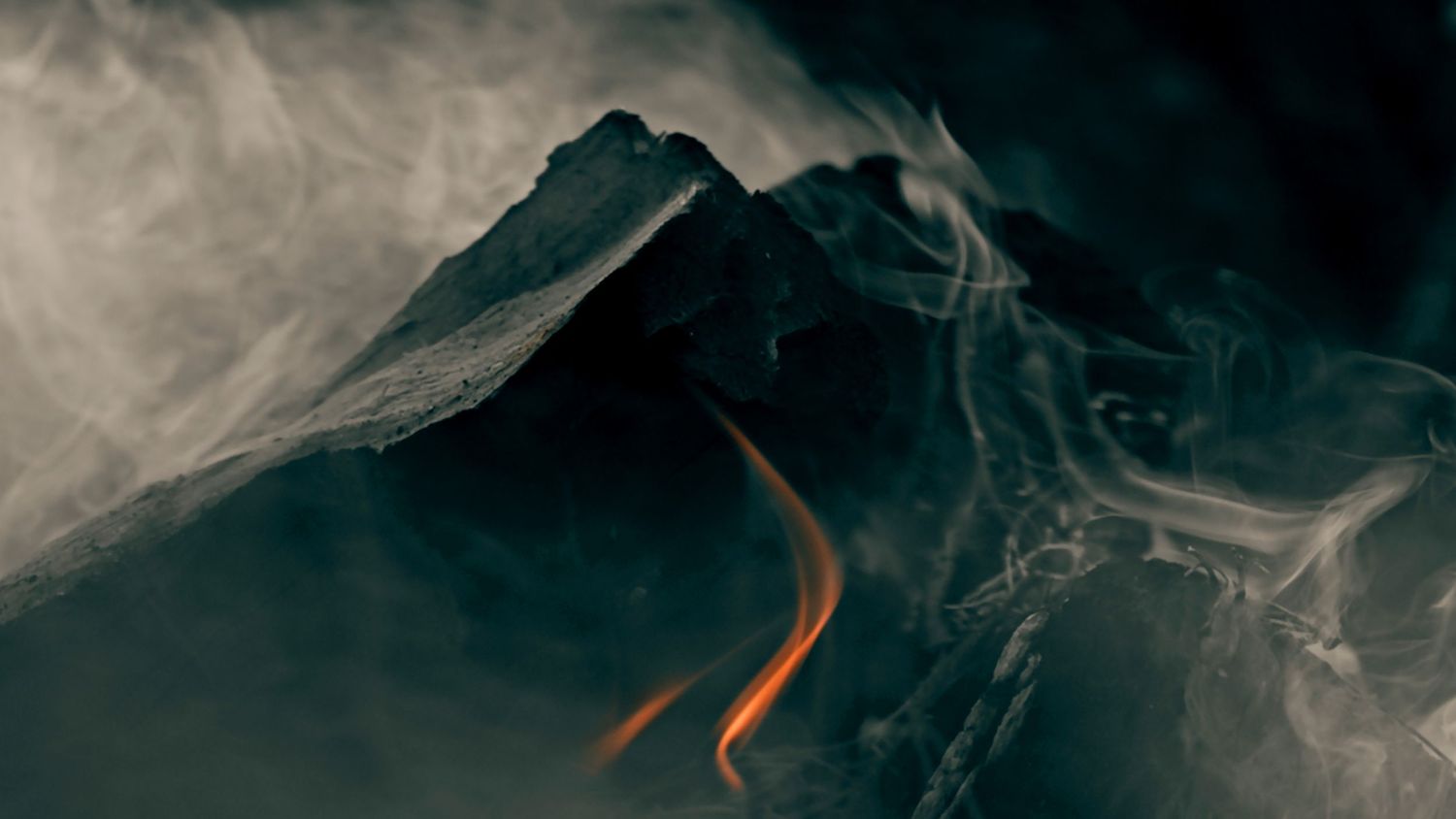 A dark mountain peak with glowing orange lava flow and swirling smoke against a moody backdrop.