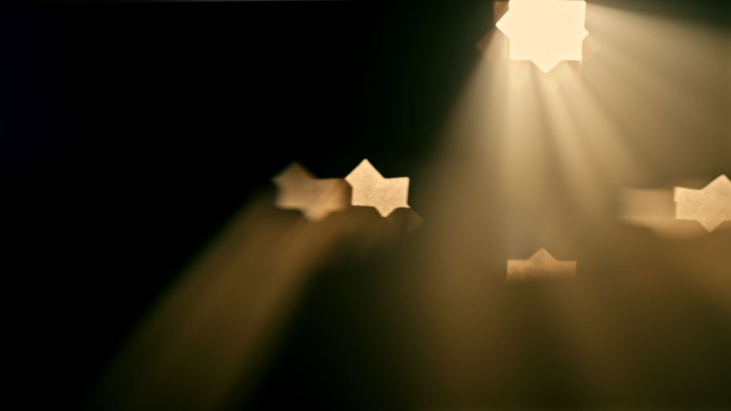 Beams of sunlight filter through clouds creating dramatic rays of light against a dark sky.
